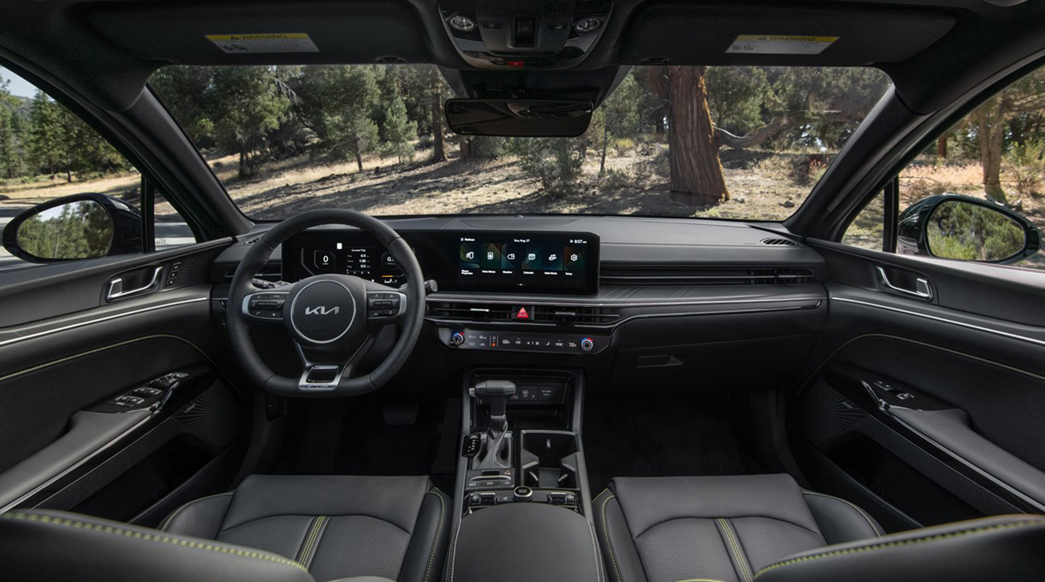 Interior view of the 2025 Kia K5 showing its ample space, steering wheel, and available 24-inch combined Panoramic Display control panel