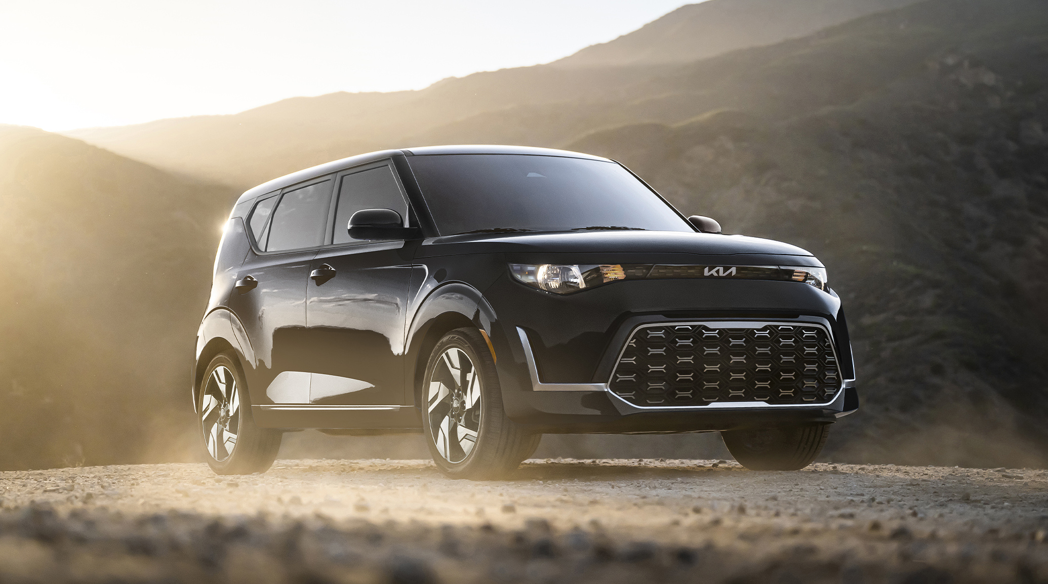 2025 Kia Soul in a three-quarter side view driving up a dirt road in the mountains