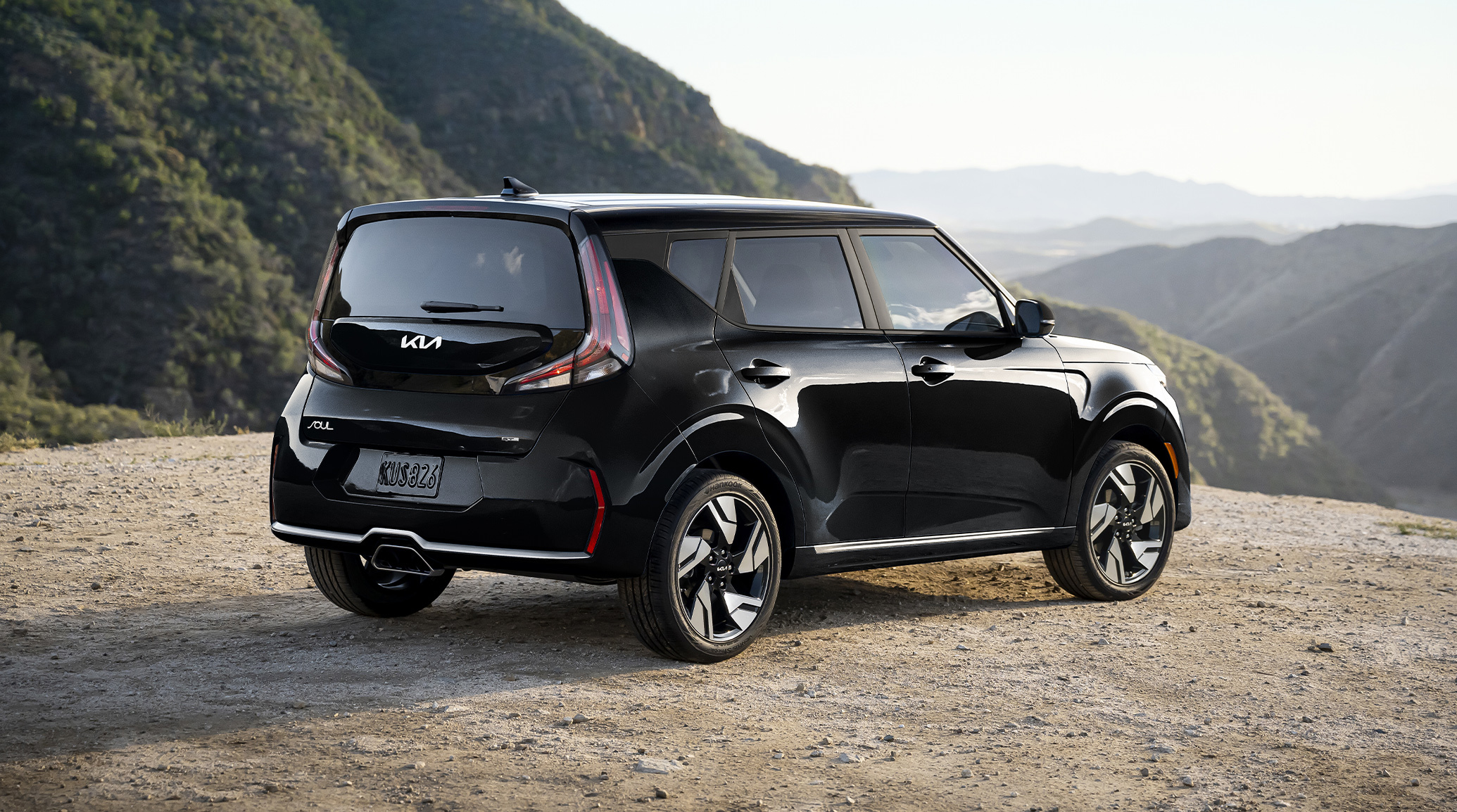 2025 Kia Soul in a three-quarter back view parked on an open road that overlooks mountains