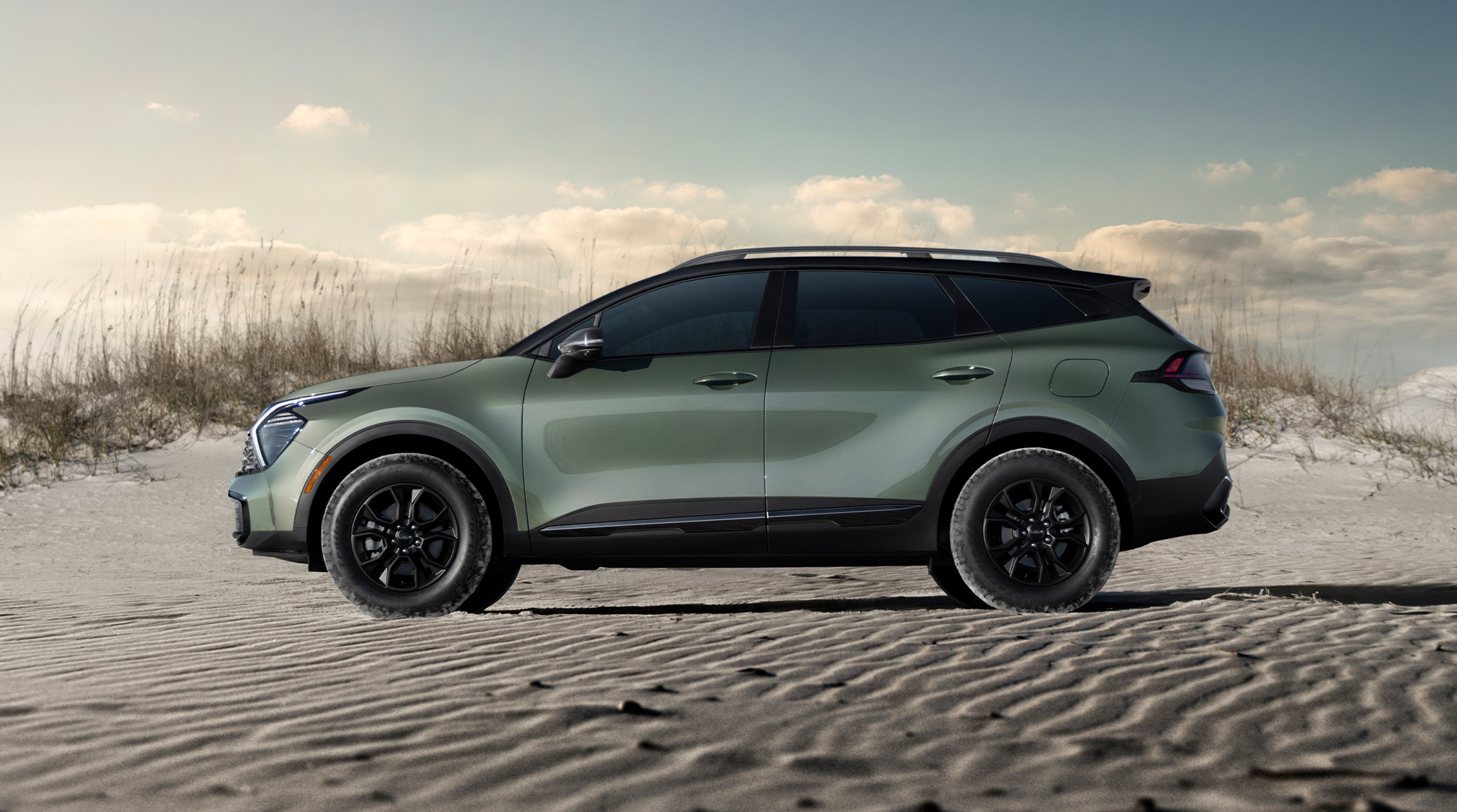 2025 Kia Sportage in green, driver side view, parked on the beach