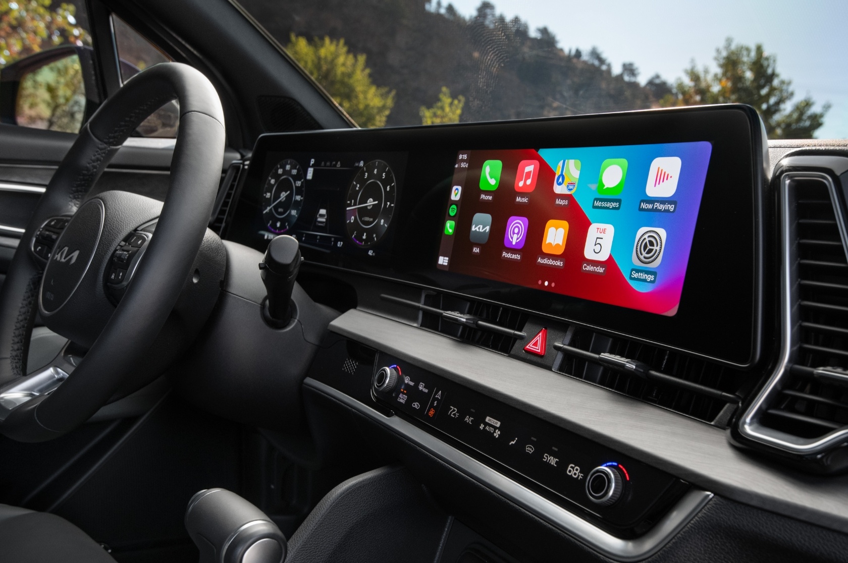 2025 Kia Sportage interior, three-quarter side view of the panoramic dual display with apps like maps, messages, and podcasts on the screen