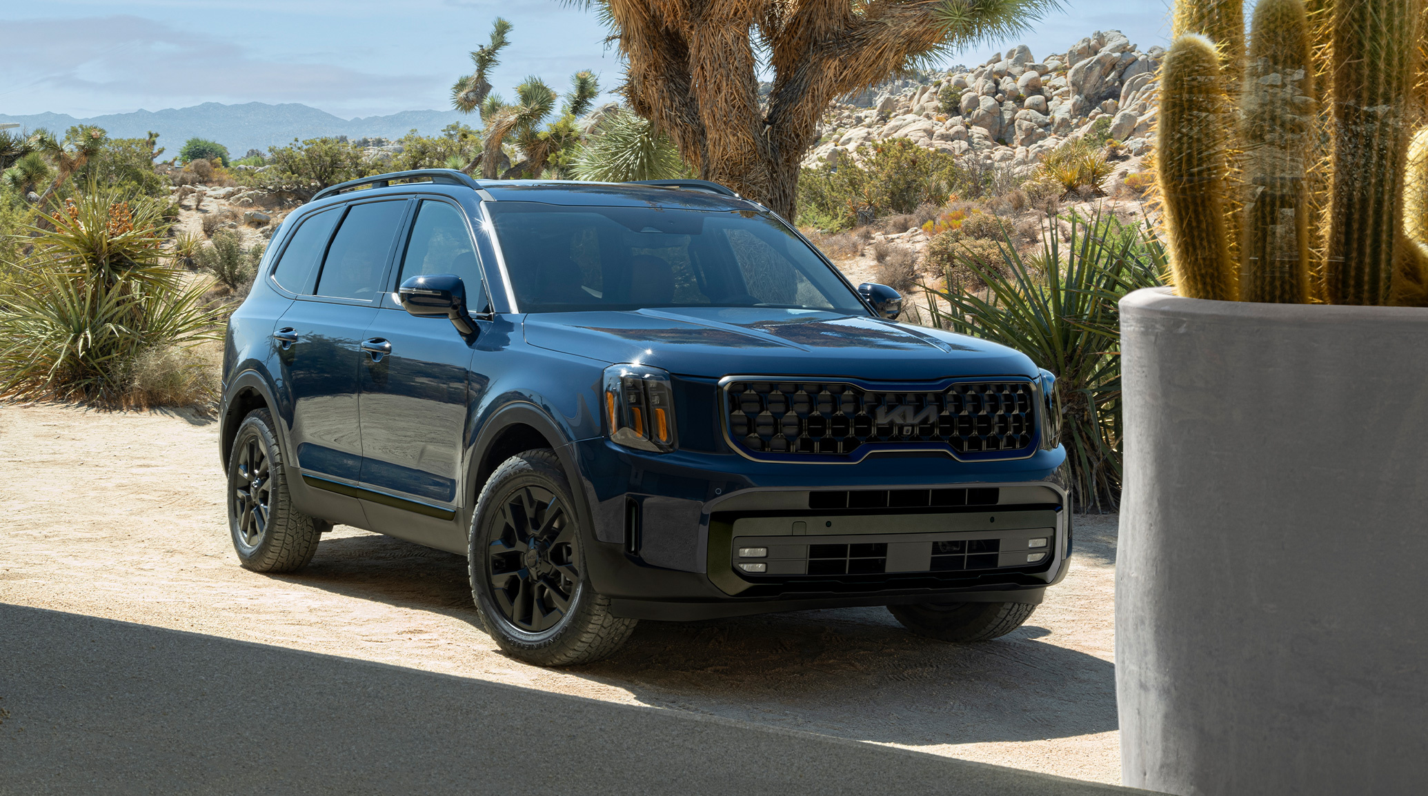 2025 Kia Telluride in a three-quarter front view, parked on a paved road in the desert