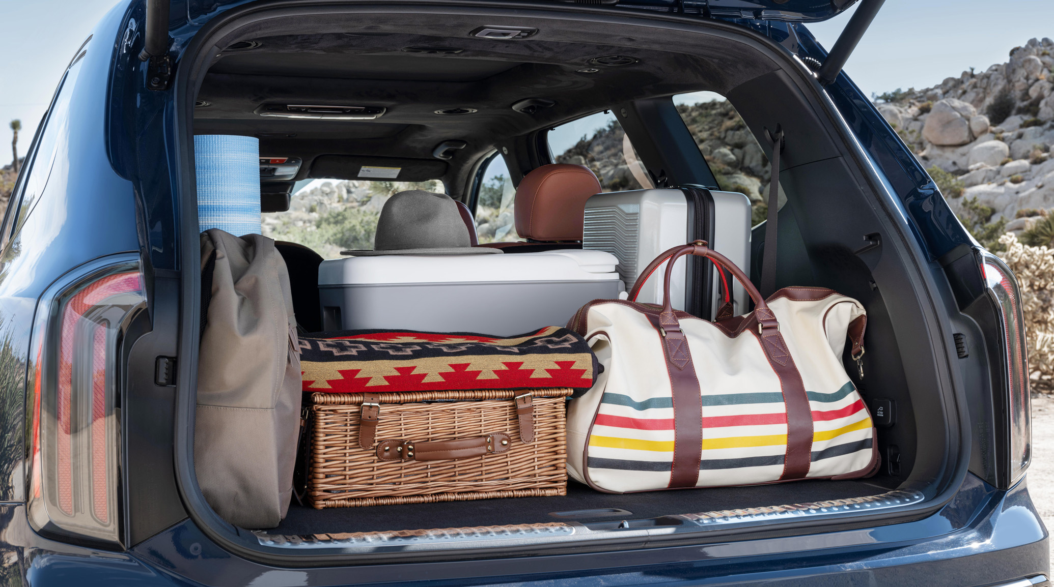 2025 Kia Telluride, view of the rear, with the liftgate open to reveal travel gear like a duffel bag, suitcase, picnic basket, cooler, and backpack