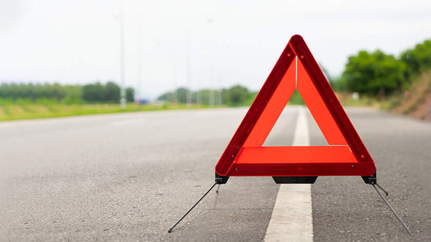 Primer plano de una señal con un triángulo de emergencia en la carretera