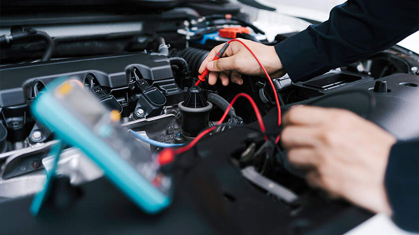 Manos de reparador inspeccionando el sistema eléctrico de un vehículo