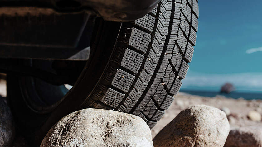 A close-up view of a tire stuck on rocks on a sandy beach
