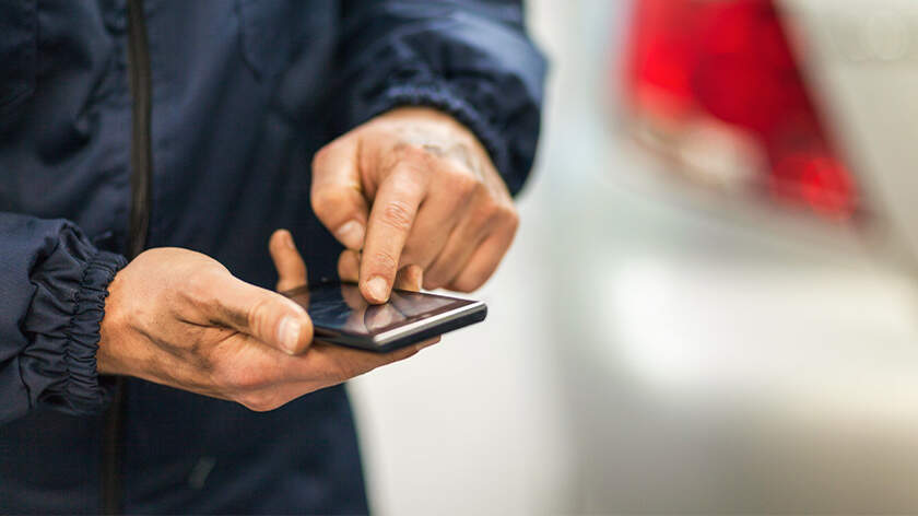 Hombre usando telefono movil al par de un auto