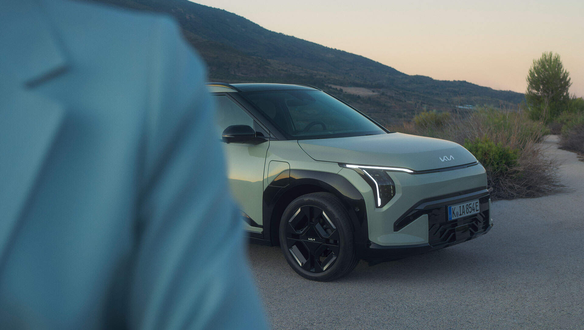 Side view of a Kia EV3 parked with mountains in the background.