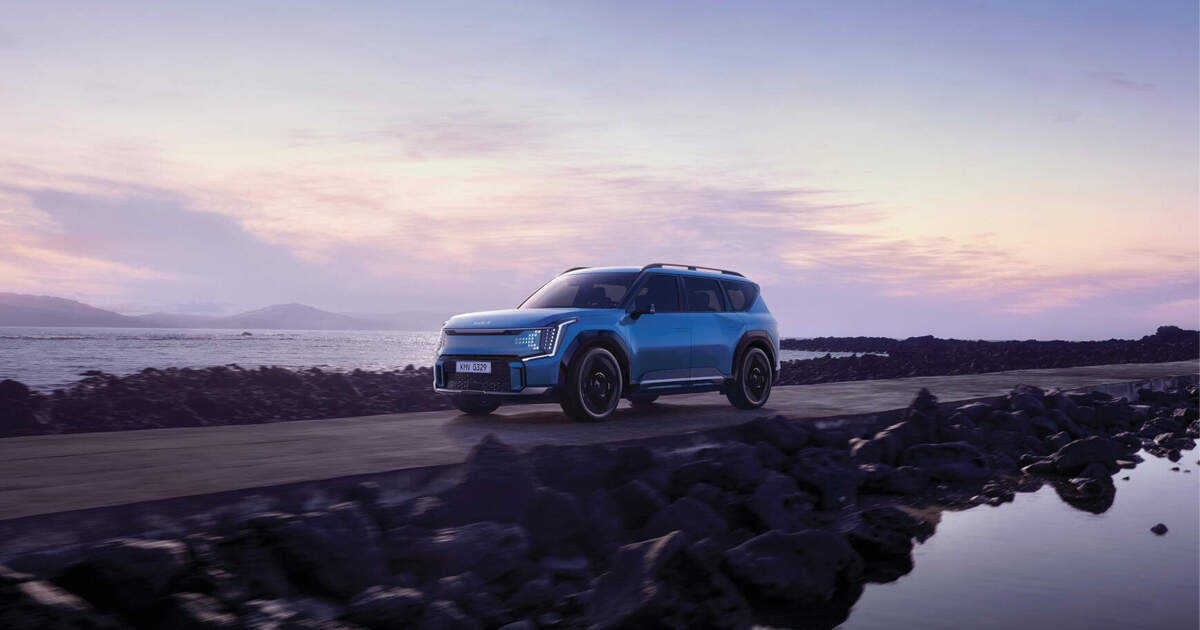 A Kia EV9 is driving on a coastal road