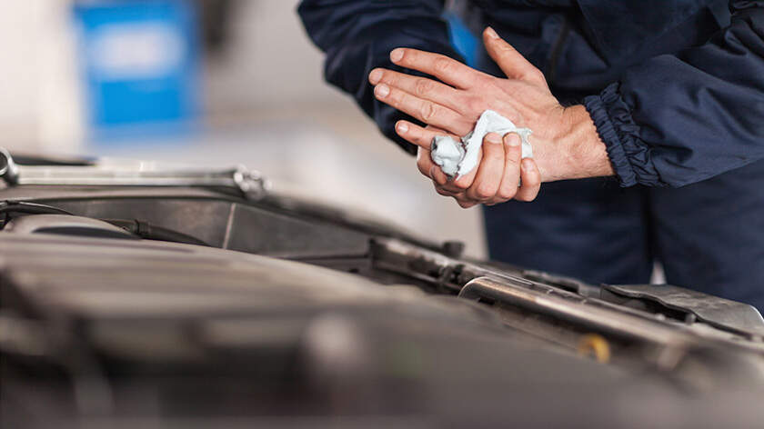 Mechanic wiping his hand in front of an open hood