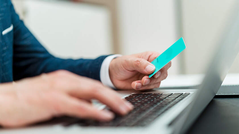 Man using laptop with credit card in his hand