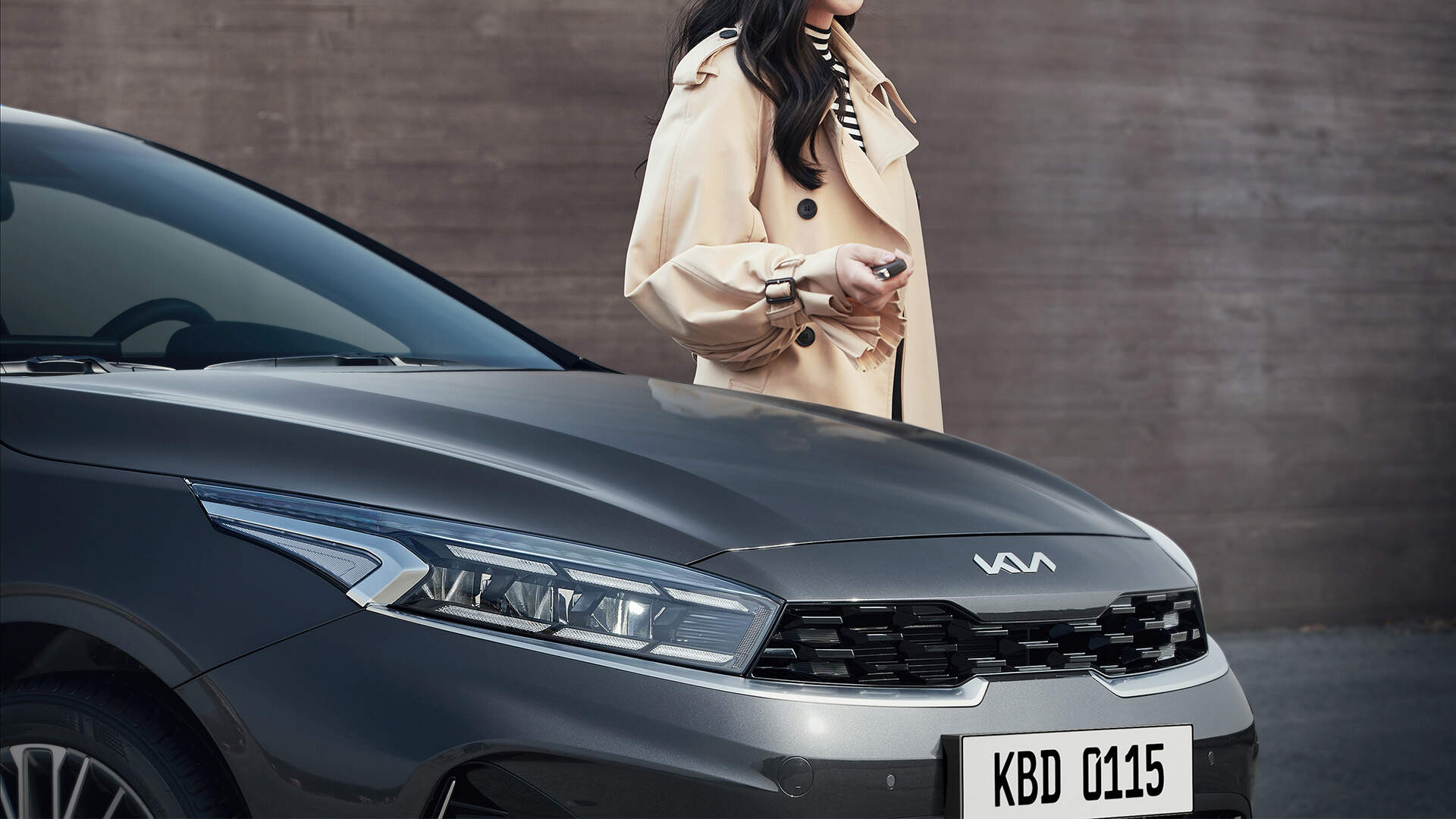 Woman holding smart key in one hand is standing next to the Cerato