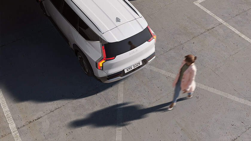 Top-down view of an EV9 reversing, with a person walking behind