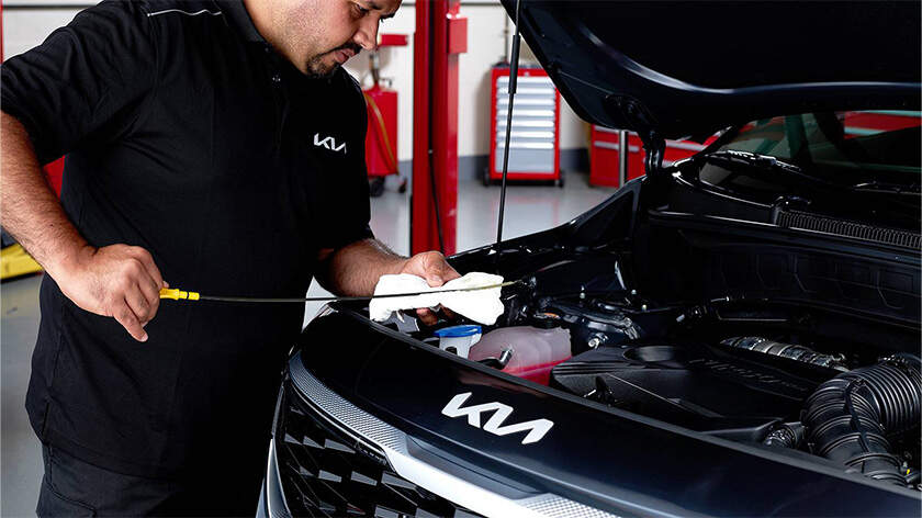 Mechanic inspecting a car with a oil dipstick