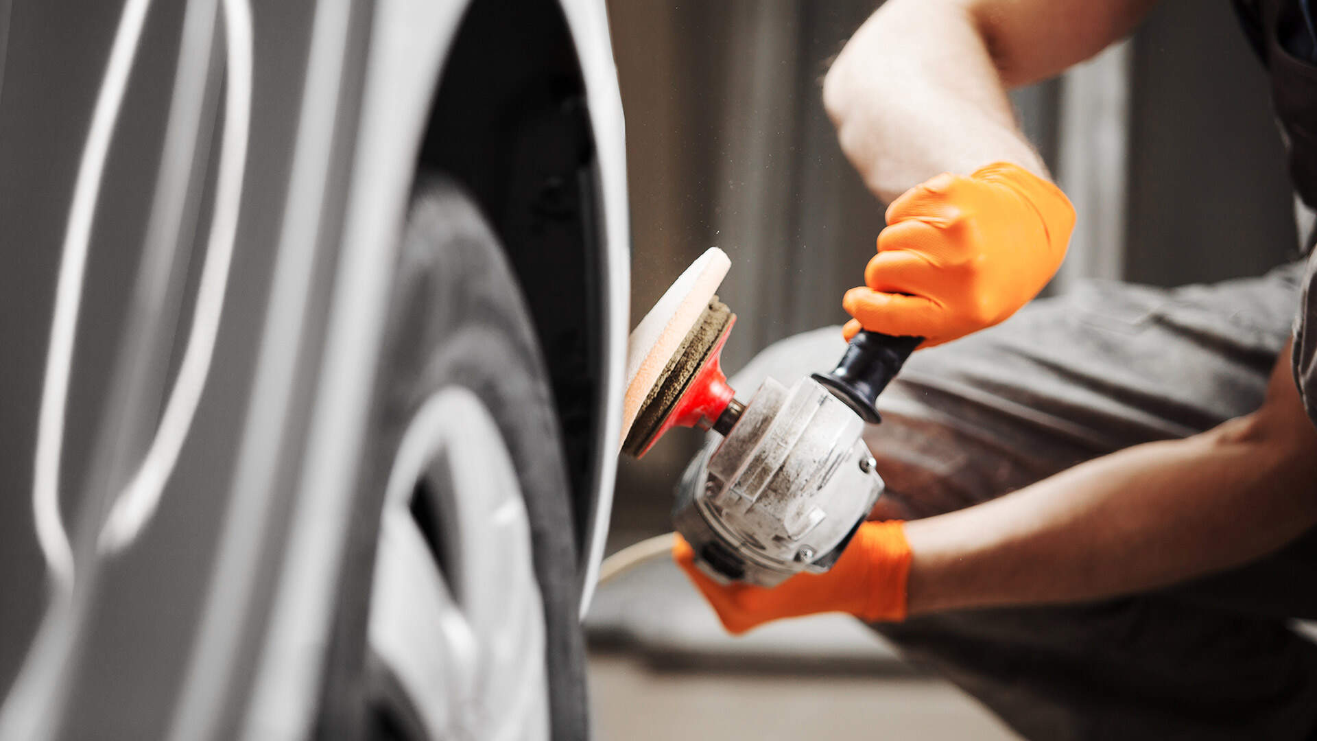 Specialist is polishing a car using a polishing machine in front of a bonnet