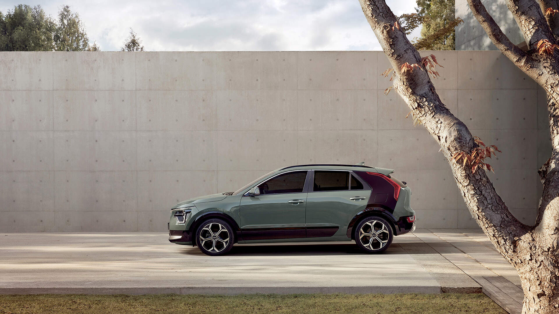 A Kia Niro is parked in front of a concrete wall