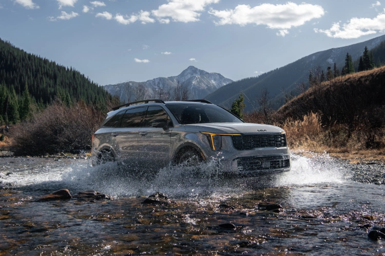 2025 Kia Sorento, three-quarter view, driving through a river making a big splash