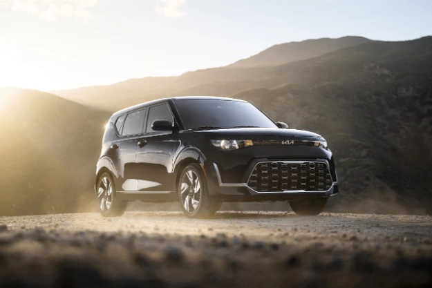 2025 Kia Soul in a three-quarter side view driving up a dirt road in the mountains