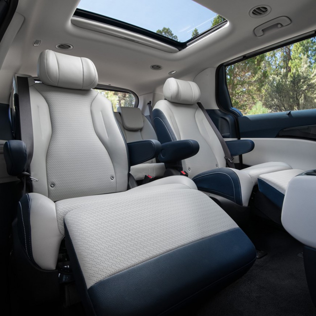 2025 Kia Carnival's second row VIP lounge seats with the leg rest extended upwards, and the sunroof hovering above, three-quarter view